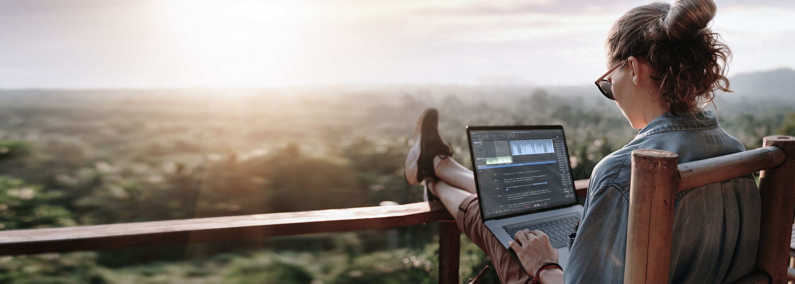 Girl on Porch Relaxed with Laptop editing in Hindenburg Pro with a view over forest landscape in bright sunrise